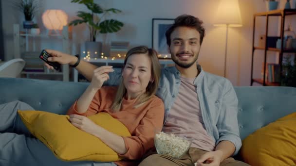 Porträtt av pojkvän och flickvän titta på rolig film på TV äta popcorn och skratta på kvällen hemma — Stockvideo