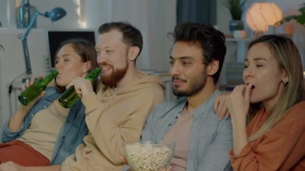 Jeune groupe multiculturel ludique regardant un film drôle à la télévision et s'amusant à la maison tard dans la nuit — Video