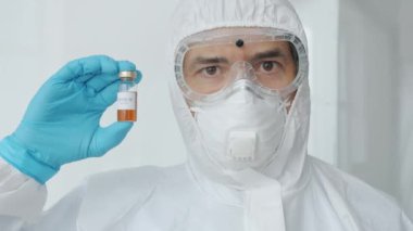 Koruyucu giysi maskeli ve solunum cihazlı doktor enfeksiyoncusunun portresi.
