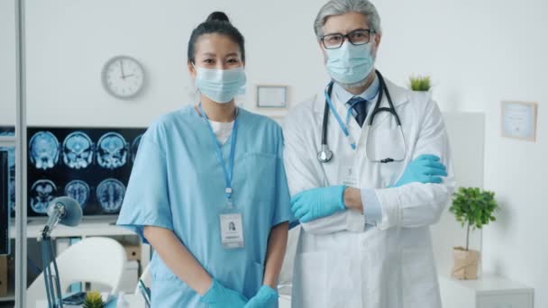 Önlüklü hemşirenin yavaş çekimde portresi ve klinikte duran beyaz önlüklü doktorun resmi. — Stok video