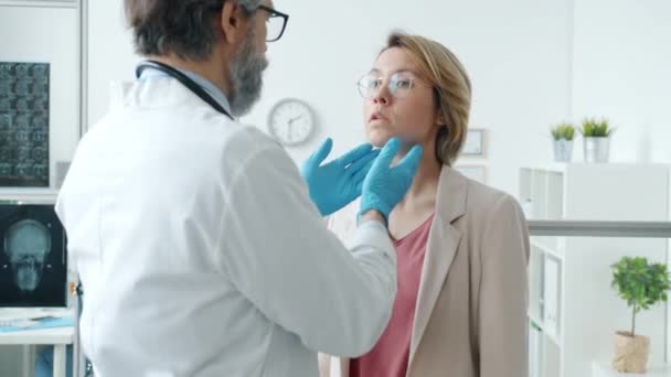 Praktikant v bílých šatech a rukavicích vyšetřující mladou ženu a mluvící s pacientem na klinice — Stock video