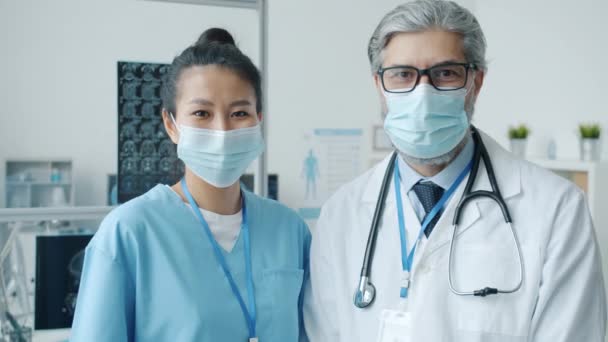 Slow motion portrait of male and female medical specialists in uniform and face mask standing in hospital room — Stock Video