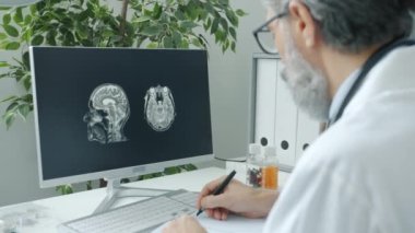 Olgun doktor bilgisayarla çalışıyor. Hastanedeki kapalı alanda beyin taraması yapıyor.