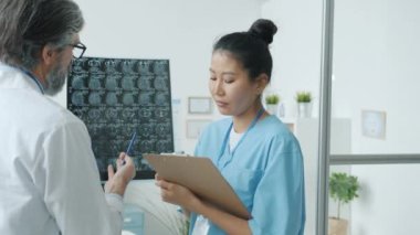 Hemşire hastanede çalışırken radyoloji uzmanı beyin taramalarını inceliyor.