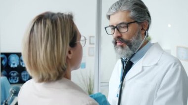 Hastane odasında steteskoplu bir kadını muayene eden deneyimli bir kardiyolog.