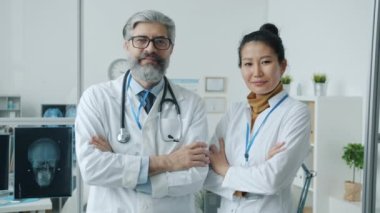 Üniformalı, kendine güvenen doktorlar modern klinikteki kameralara gülümsüyor..