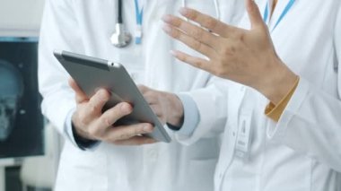 Kadın ve erkek el doktorlarının, profesyonel konuşma sırasında tablet ve el kol hareketleri kullanarak yakın plan çekimleri.