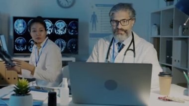 Doktorlar ciğerlere bakıyor MRI taramaları yapıyor ve geceleri karanlık ofiste teşhisi tartışıyorlar.