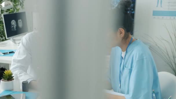 Doctor and nurse using tablet touching screen and talking working in hospital office — Stock Video