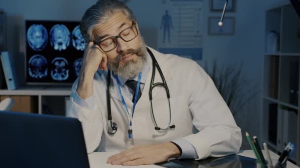 Portrait of tired male doctor sleeping waking up working with laptop in dark office at night — Stok Video