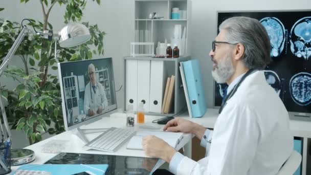 Orvosok kollégák, hogy az online video hívás beszélő integető kéz segítségével PC a kórházban — Stock videók