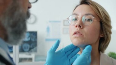 Eldivenli doktorların yakın çekimi klinikteki genç bayana tıbbi muayene yapıyor.