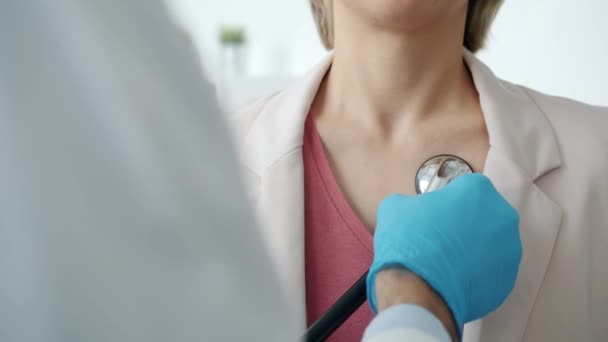 Close-up de médicos mão na luva examinando paciente feminino com estetoscópio durante consulta médica no hospital — Vídeo de Stock