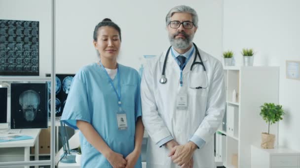 病院のスタッフの男と女のスローモーションポートレート現代オフィスに立って — ストック動画