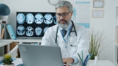 Hastane ofisindeki masada daktilo kullanan ciddi bir yetişkin doktor.