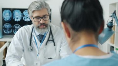 Olgun doktorların hemşirelerle hastanede iş hakkında konuştuğu bir fotoğraf.