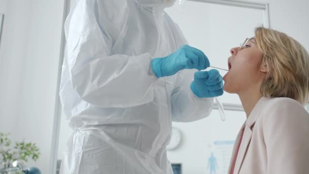 Koruyucu giysili doktor kadın hastayı hastane laboratuvarında korona virüsü enfeksiyonu için test ediyor. — Stok video