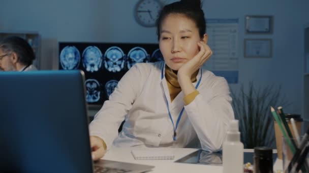 Portret lent al obosit asiatic doamnă doctor folosind laptop și somn în birou întunecat pe timp de noapte — Videoclip de stoc