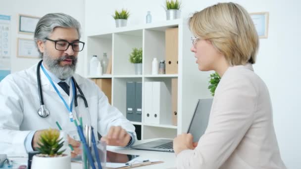 Médecin amical donnant de bonnes nouvelles à la patiente parlant en souriant montrant un scanner IRM à la clinique — Video