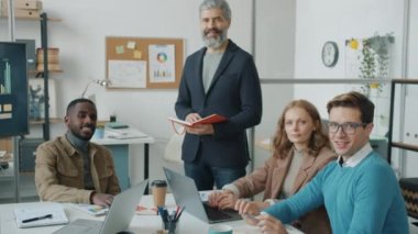 Modern ofisteki yaratıcı ofis çalışanlarının portresi mutlu yüzlü kameraya bakıyor.