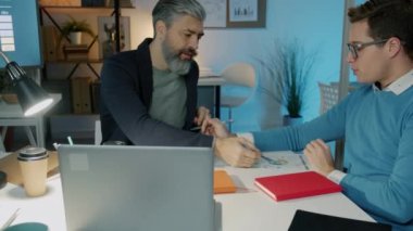 Hırslı iş adamları ve kadınlar akşamları modern ofiste iş konuşuyorlar.