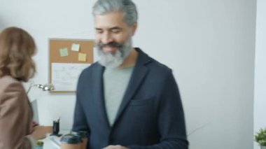 Arkadaş canlısı ofis çalışanı iş arkadaşına kahve getiriyor sonra da laptopla birlikte çalışıyor.