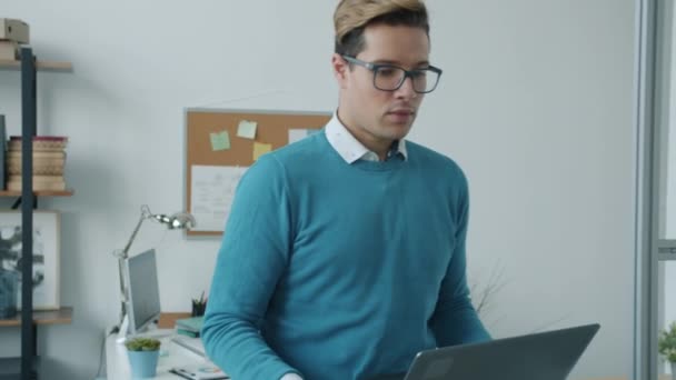 Slow motion av affärsman promenader i kontor bär bärbar laptop sedan prata med kvinnlig kollega — Stockvideo