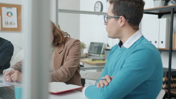Lidé kolegové mluvit a kontrolovat informace v notebooku sedí na stole v kanceláři — Stock video
