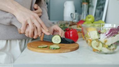 Dört el erkek ve kadın evde mutfakta salata pişirmek için sebze kesiyorlar.