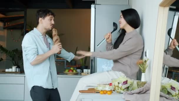 Młody mężczyzna i kobieta śpiew taniec zabawy w kuchni w mieszkaniu — Wideo stockowe