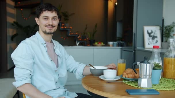 Портрет повільного руху чоловіка, який сидить за кухонним столом з їжею посміхається — стокове відео