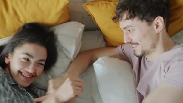 Joven hombre cosquillas novia en la cama divertirse riendo juntos en casa — Vídeo de stock