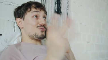 Mutlu öğrenci portresi cep telefonuyla konuşuyor ve yatak odasında gülümsüyor.