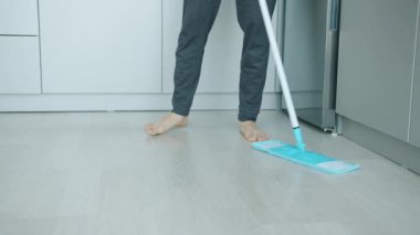 Erkek bacaklarının mutfak zeminini temizlerken modern paspasın ev işlerini tek başına yapması.