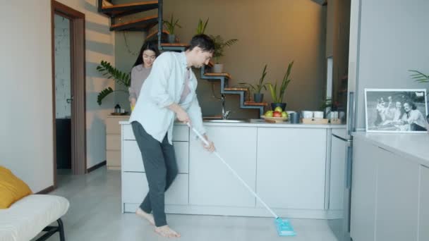 Krásný mladý pár dělá úklid v kuchyni mytí podlahy a nábytku — Stock video