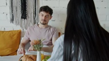 Bakıcı adam kız arkadaşını kruvasanla besliyor ve evde meyve suyu içiyor.