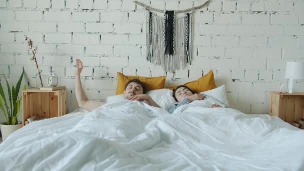 Esposo y esposa despertando en pánico comprobando el tiempo y corriendo fuera del dormitorio — Vídeo de stock