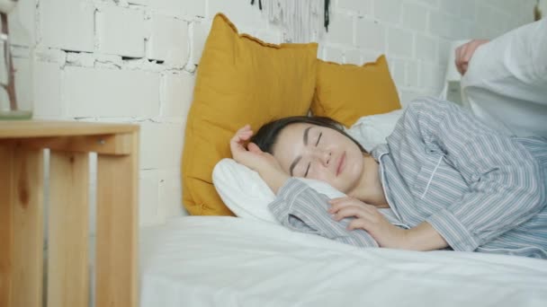 Турбота про чоловіка, що вкриває сплячу дружину ковдрою і цілується в спальні вдома — стокове відео