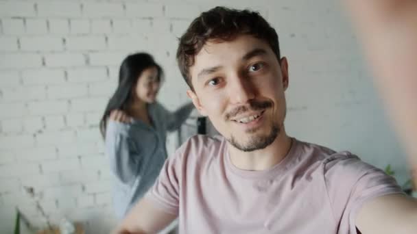 Portret van een man die online video oproep van slaapkamer praten terwijl gelukkig vrouw springen op bed — Stockvideo