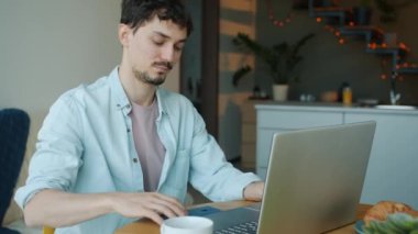 Bilgisayarla çalışan ve cep telefonuyla konuşan hırslı bir gencin portresi.