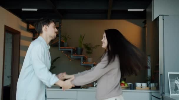 Mulher asiática e homem de raça biracial dançando e se divertindo juntos na cozinha moderna — Vídeo de Stock