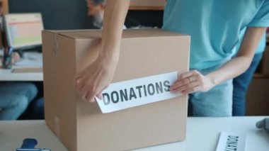 Gönüllü yardım paketleri insani yardım için düşünürken bağış etiketini hayır organizasyonundaki karton kutunun üzerine yapıştırmak.