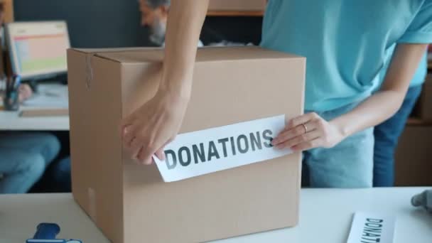 慈善组织将捐款标签贴在纸板箱上的特写镜头 志愿者在包装时考虑人道主义援助 — 图库视频影像
