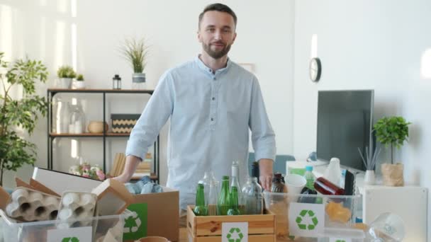Porträt Eines Lächelnden Typen Der Einer Wohnung Mit Recyclingcontainern Voller — Stockvideo