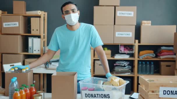 中东志愿者头戴口罩 站在餐桌旁边 带着食品杂货 准备在慈善公司捐赠 为饥饿和大流行病提供食物的概念 — 图库视频影像