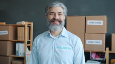 Gönüllü bir adamın yavaş hareket eden portresi kalp hareketi yapıyor ve hayır kurumunda gülümsüyor. Gönüllü olmak ve olumlu duygu kavramı.