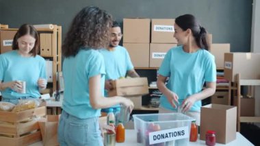 Yoksulları ve muhtaçları doyurmak için bağış kutularını yiyeceklerle dolduran bir grup hayır kurumu çalışanı. Üniformalı gençler birlikte çalışıyor ve konuşuyor..