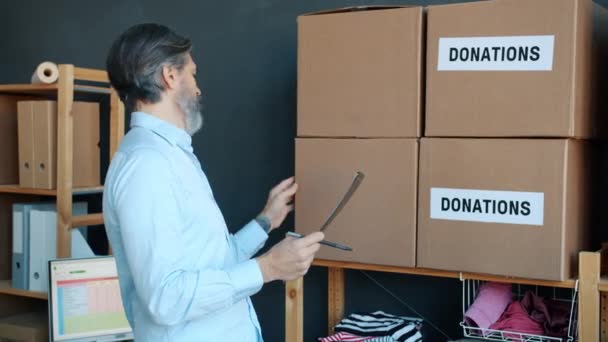成熟人士慈善基金经理在办公室的剪贴板上记录捐款方框 社会服务和人的概念 — 图库视频影像
