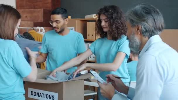 Diverso Grupo Voluntarios Empacando Cajas Con Ropa Para Donaciones Trabajando — Vídeo de stock