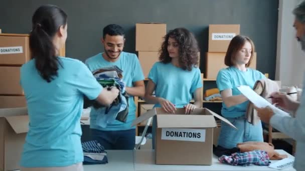 Team Van Activisten Inpakken Kleding Voor Donatie Praten Vrijwilligerswerk Liefdadigheidsfonds — Stockvideo